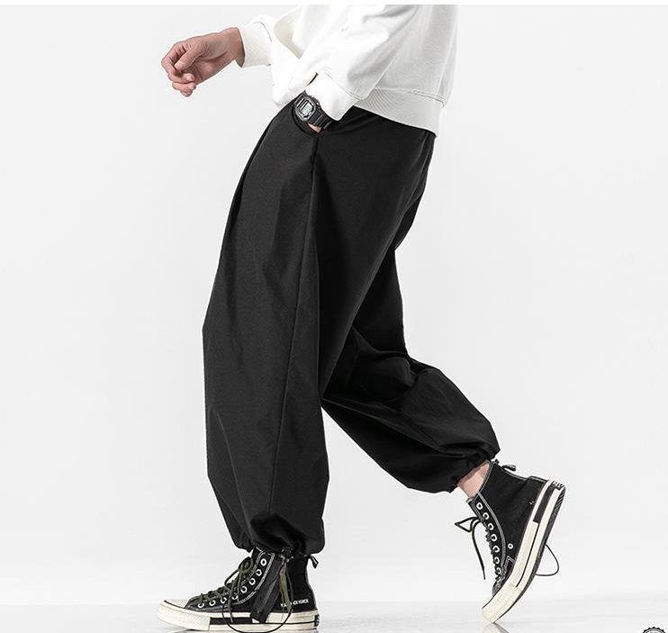 Person wearing black wide-leg pants and black high-top sneakers on a white background