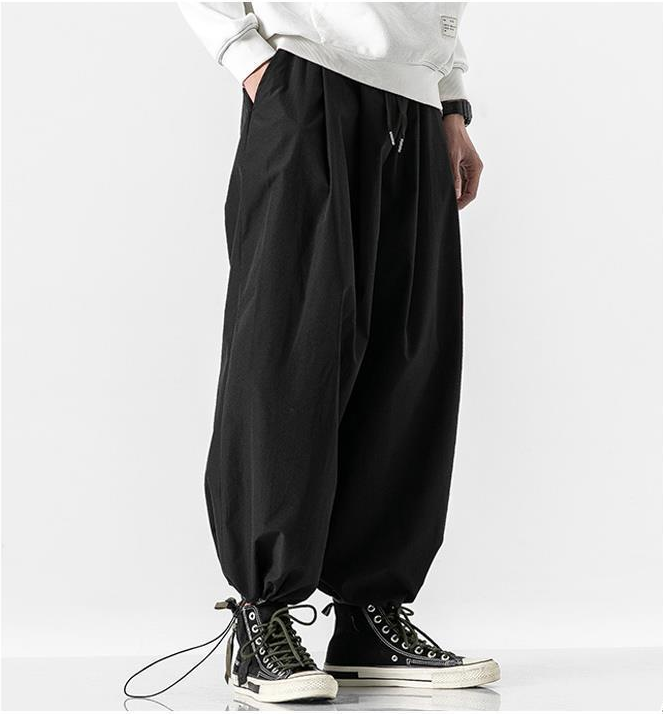 Person wearing black baggy pants and black high-top sneakers on a white background