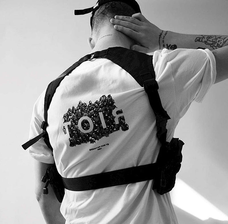 Person wearing a white t-shirt with a graphic design and a black backpack on a plain background