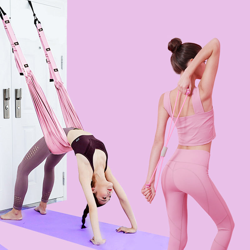 Two women practicing yoga with pink antigravity bags against a pink wall.