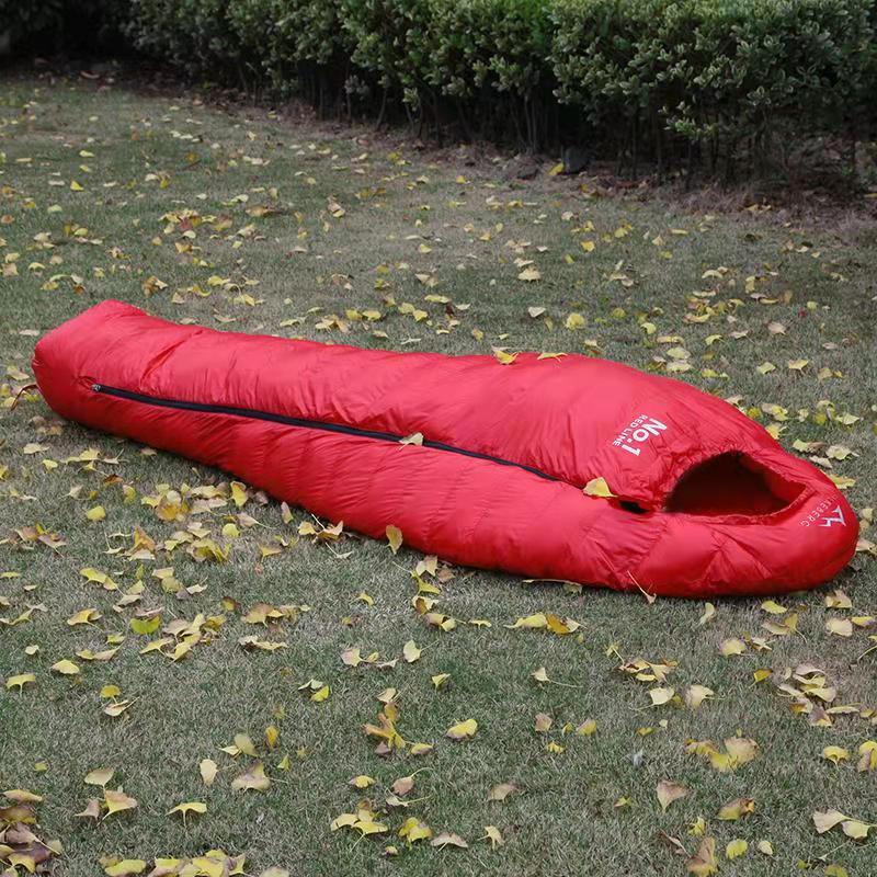 Red sleeping bag on grass with fallen leaves