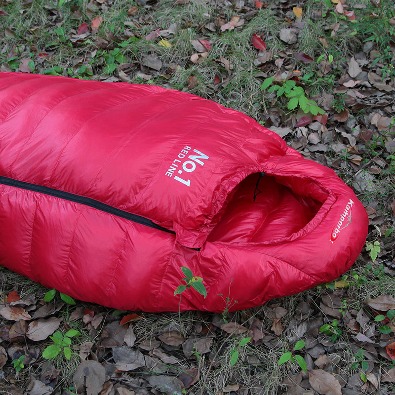 Red sleeping bag on the ground with visible branding