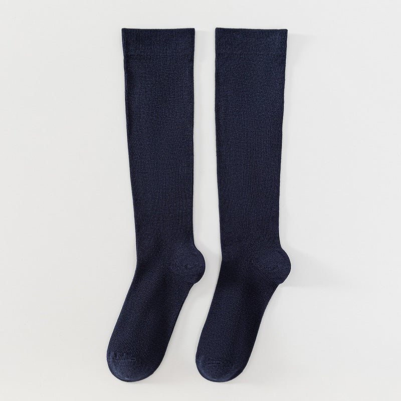 A pair of dark navy blue ribbed knee-high socks laid flat on a light gray background.