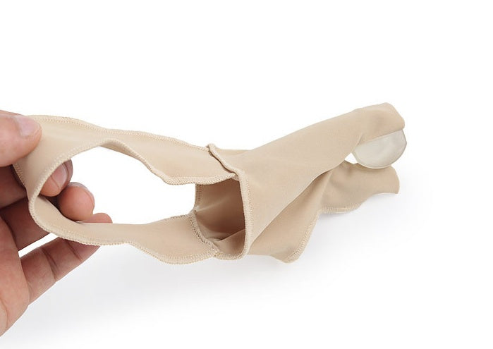 Beige silicone breast form held by a hand on a white background