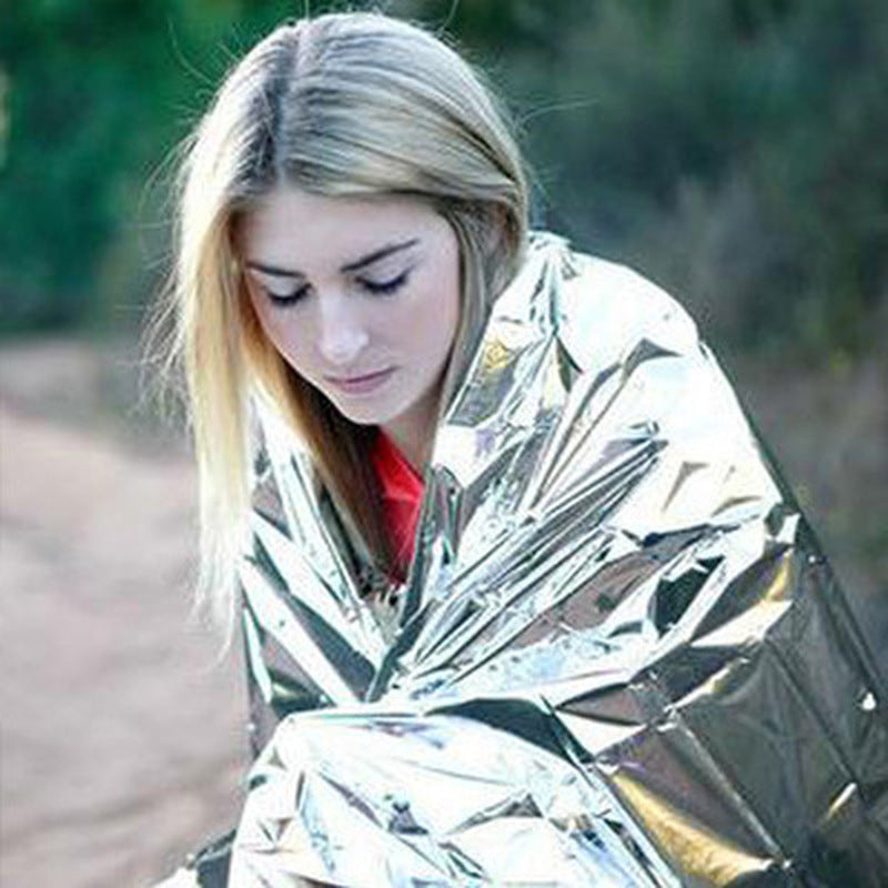 Person wrapped in a reflective emergency blanket outdoors