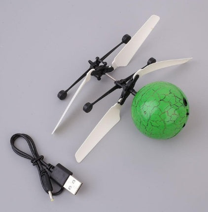 Toy helicopter with green ball and USB cable on gray background