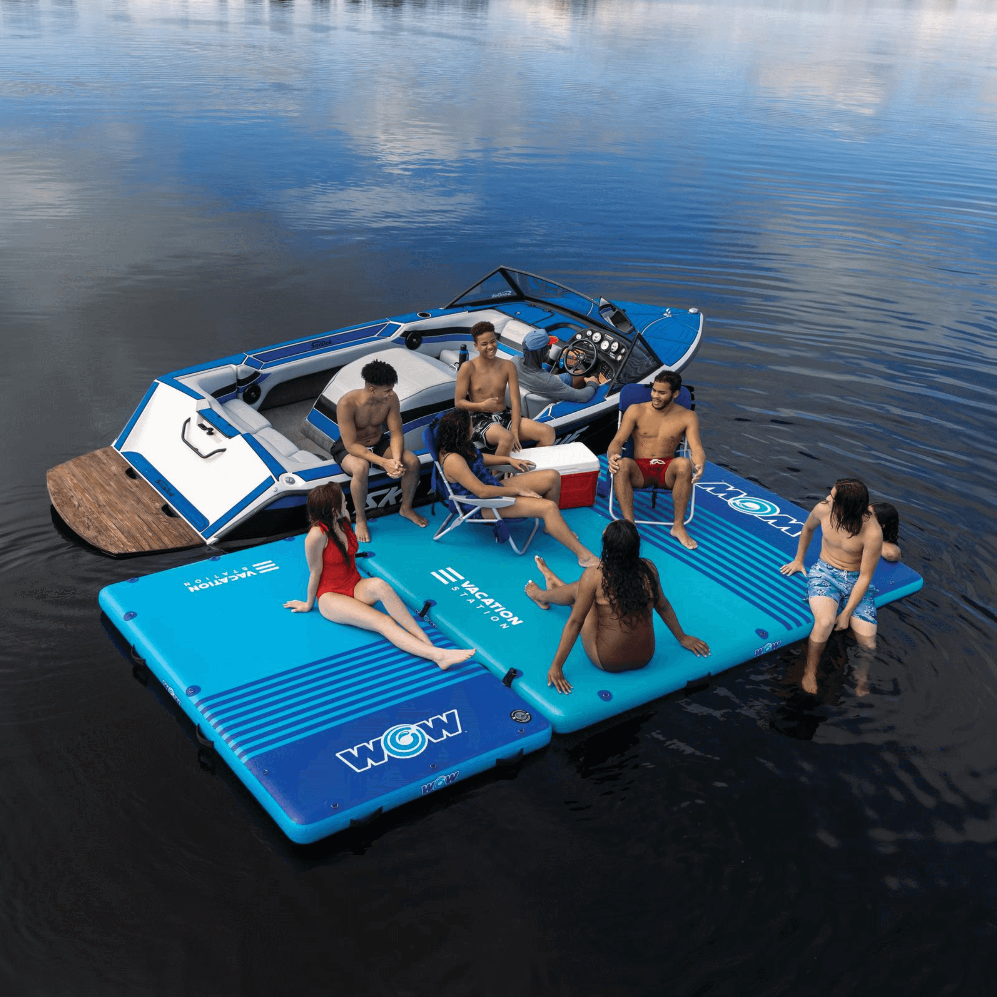 Group of people on a blue inflatable platform in the water with a boat in the background.