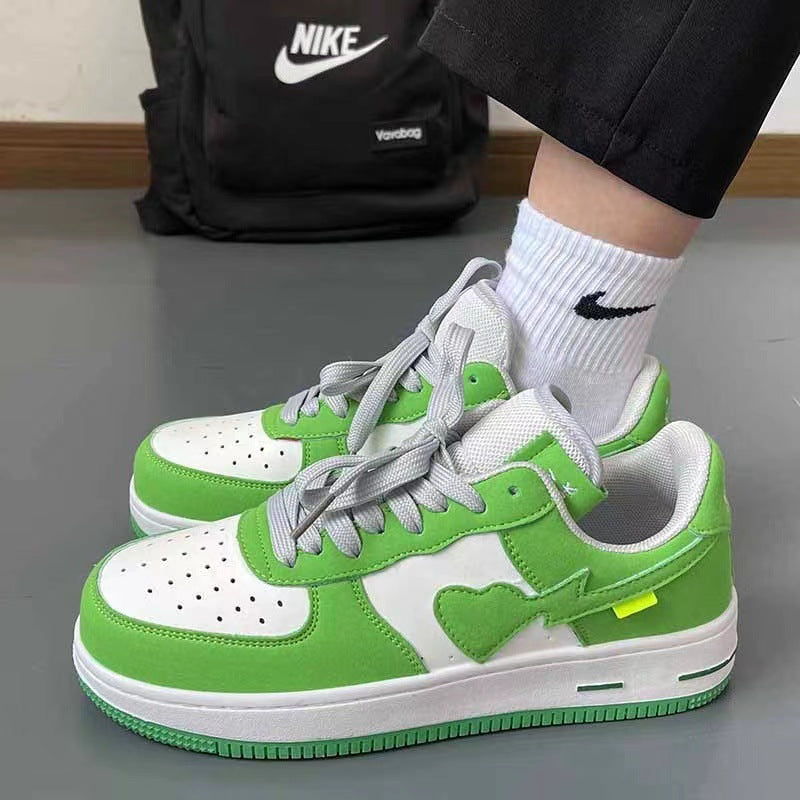 Green and white sneakers with heart design worn by a person, with a Nike backpack in the background.