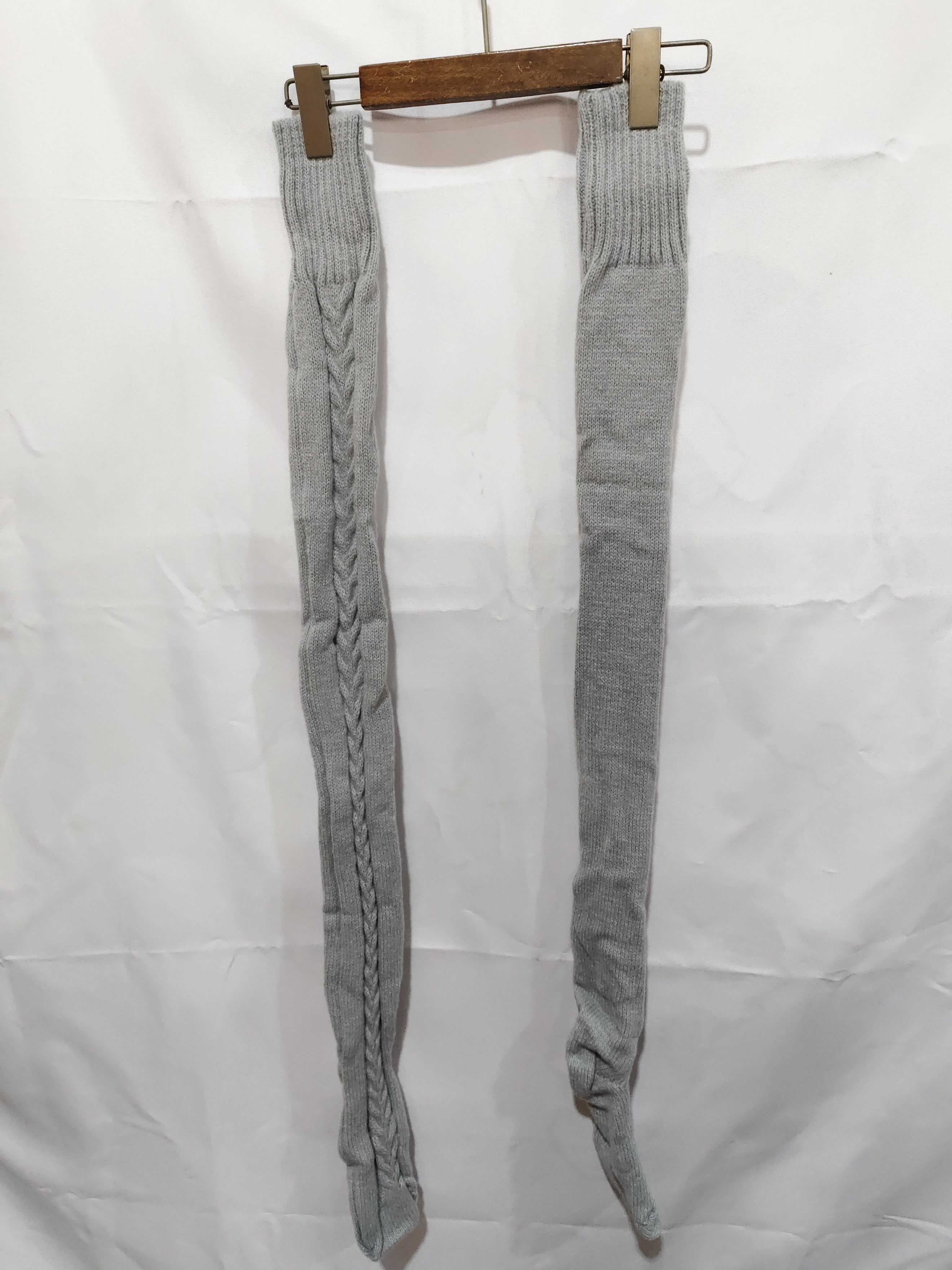 Gray knitted leg warmers on a hanger against a white background