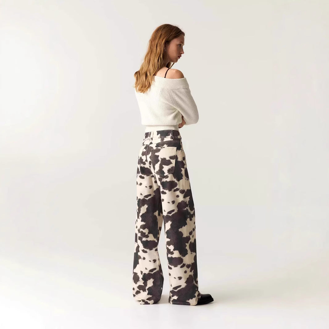 Woman wearing a white off-shoulder top and patterned pants on a plain background