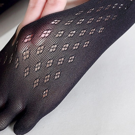 Black sheer glove with a pattern on a light gray background