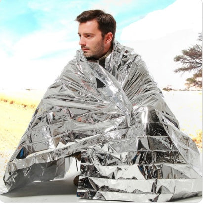 Person wrapped in a silver mylar blanket outdoors