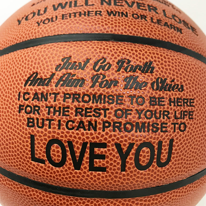 Close-up of an orange basketball with black printed text and black seam lines. The visible text reads, 'Just Go Forth And Him For The Shits I CAN'T PROMISE TO BE HERE FOR THE REST OF YOUR LIFE BUT I CAN PROMISE TO LOVE YOU'.