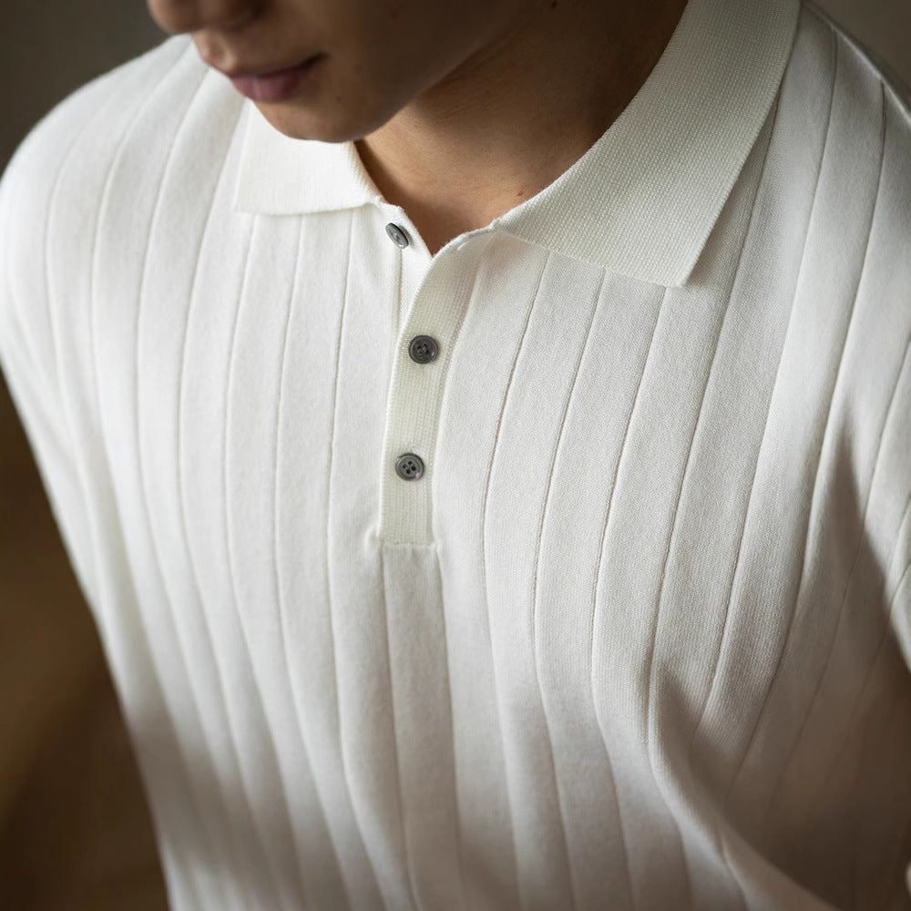 Close-up of a person wearing a white polo shirt with buttons.