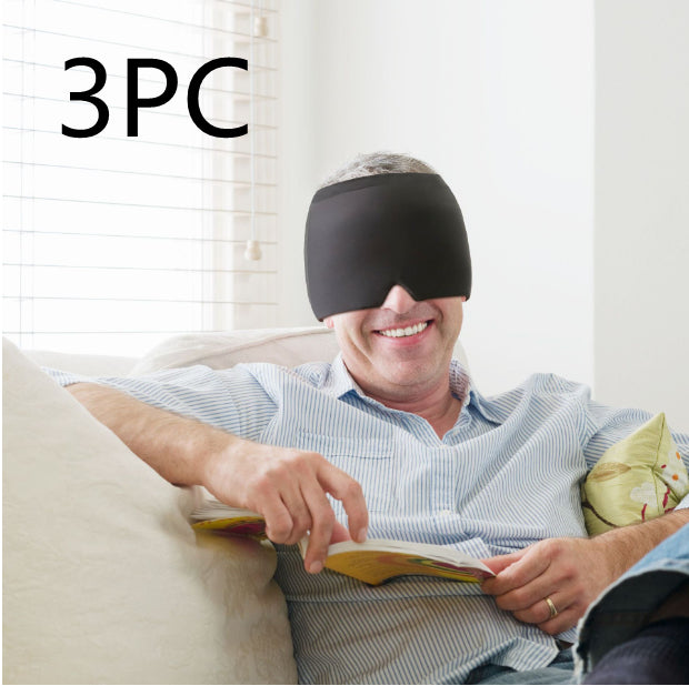Man wearing a black sleep mask while reading a book on a couch.