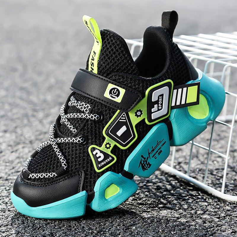 Black and turquoise children's sneakers with neon accents on a textured surface.