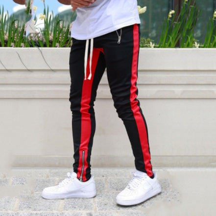 Black and red striped pants with white sneakers on a neutral background