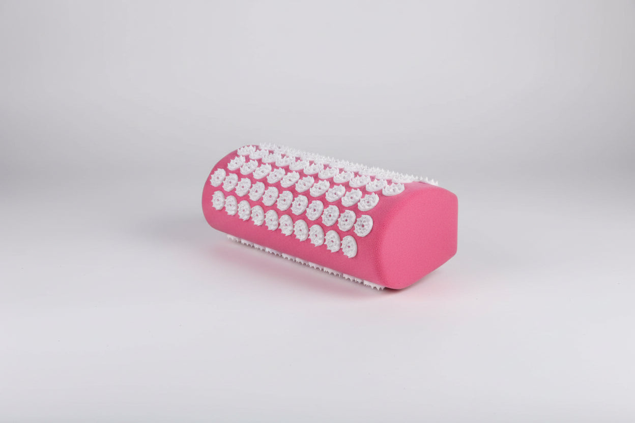 Pink cylindrical pillow with white beads on a white background