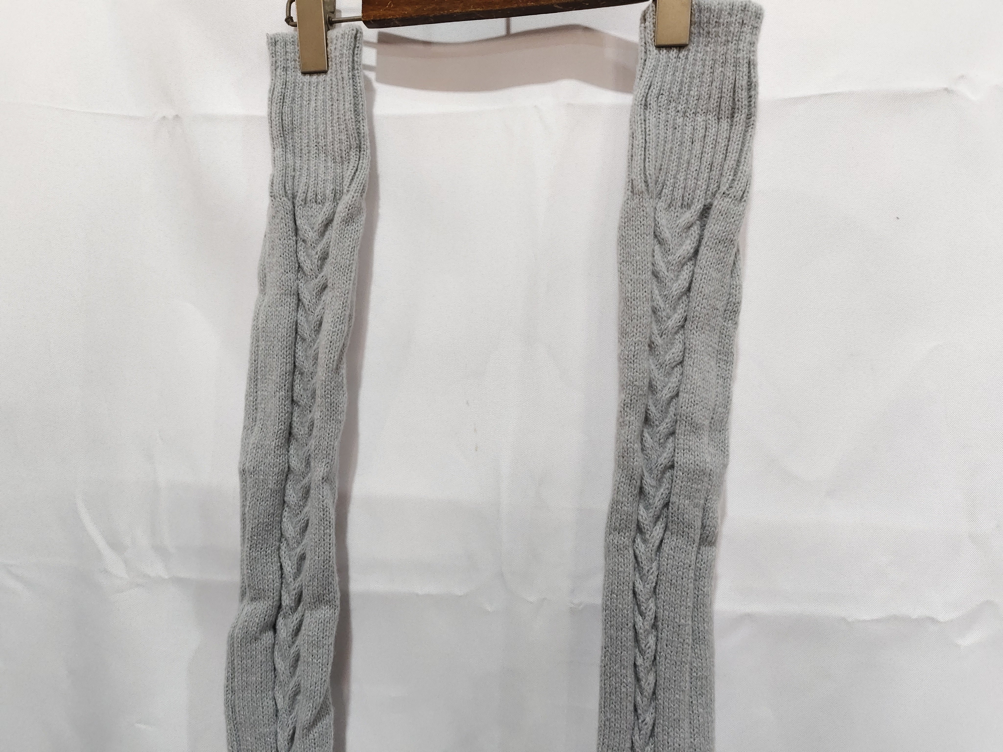 Gray knitted leg warmers hanging on a white background