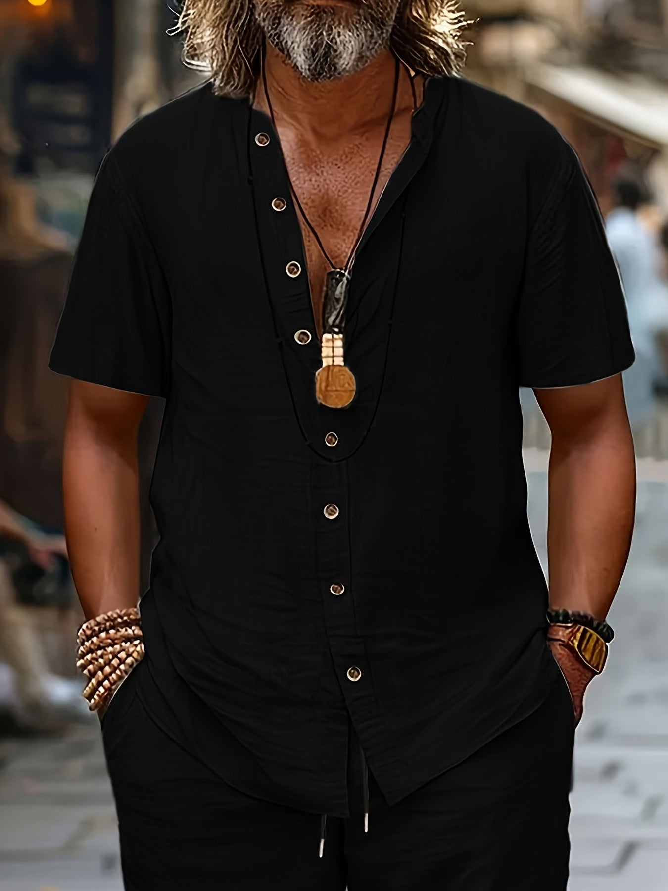 Man wearing a black short-sleeve shirt with buttons, standing outdoors.