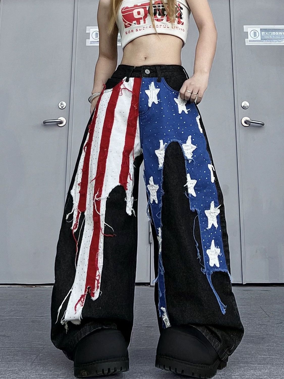 Person wearing a unique outfit with American flag design pants in front of a gray door.