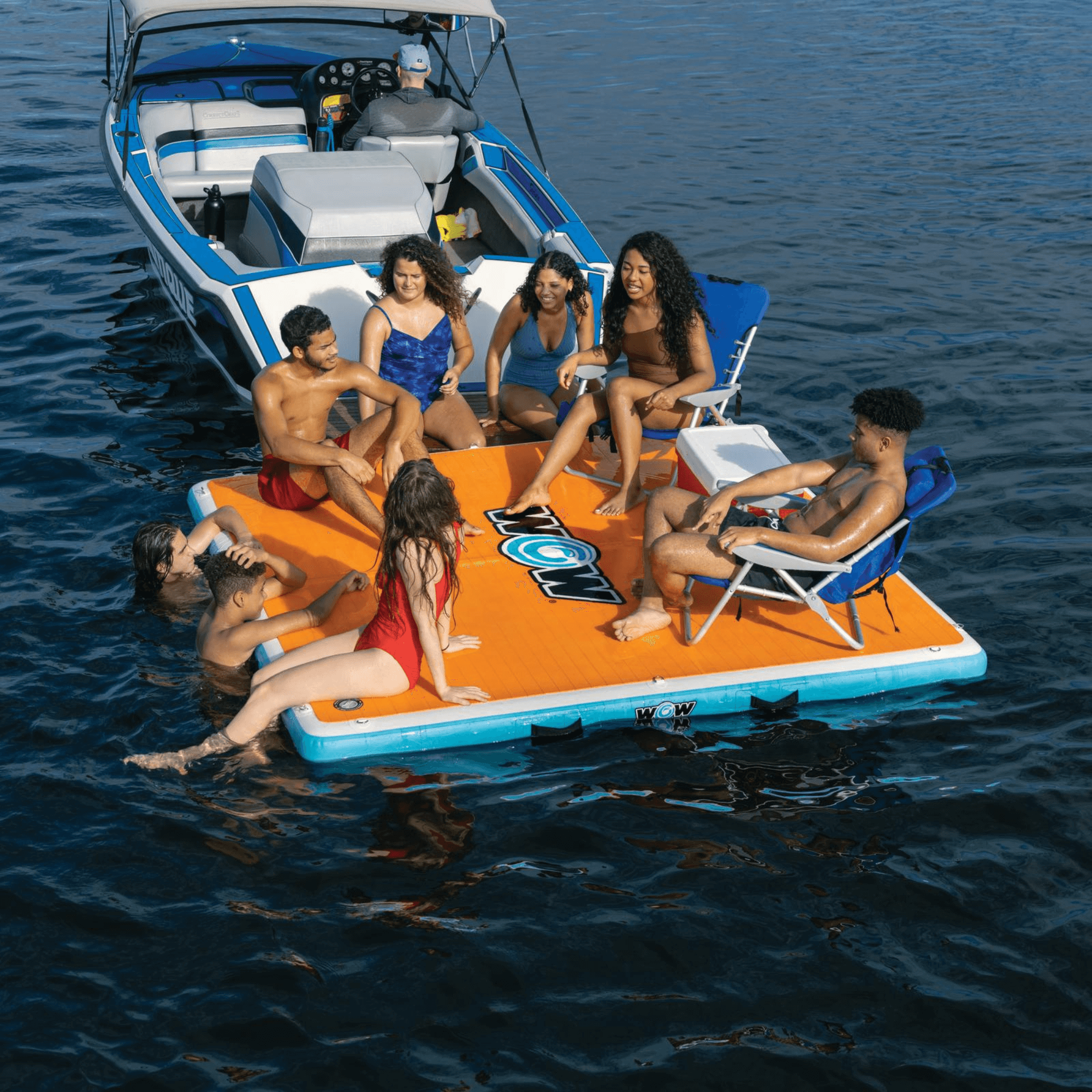 People enjoying a day out on a large inflatable platform with a boat in the background.