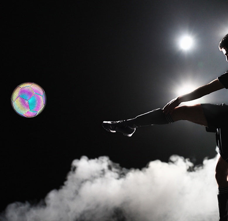 Person juggling a colorful ball against a dark background with a bright light source.