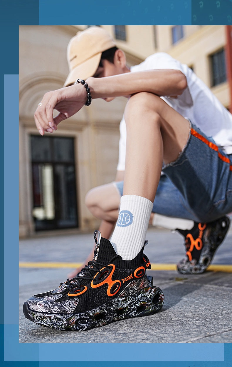 Person wearing black and orange sneakers with a white sock featuring a logo, sitting on a bench.