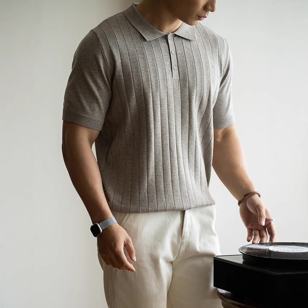 Person wearing a gray ribbed polo shirt and beige pants, standing against a plain background.