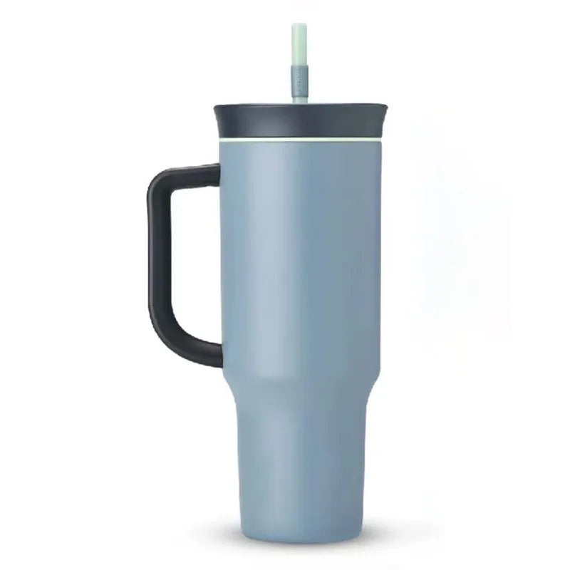 Blue-gray travel tumbler with dark handle and lid, and a pale green straw on a white background.
