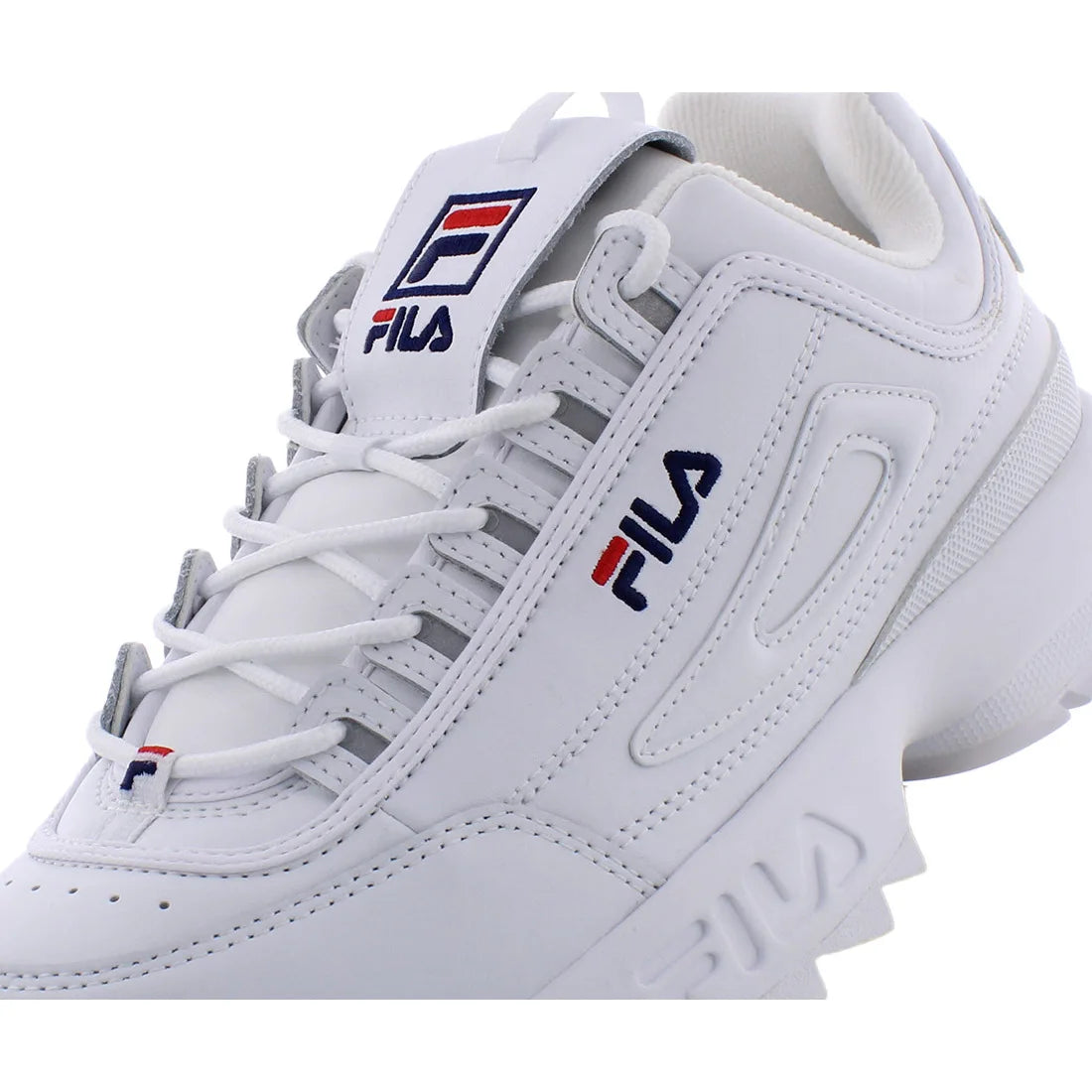 A white FILA low-top sneaker shown in a close-up side profile on a clean white background. The shoe features white leather panels, white laces, and the signature FILA logo in navy blue and red on the side and tongue.