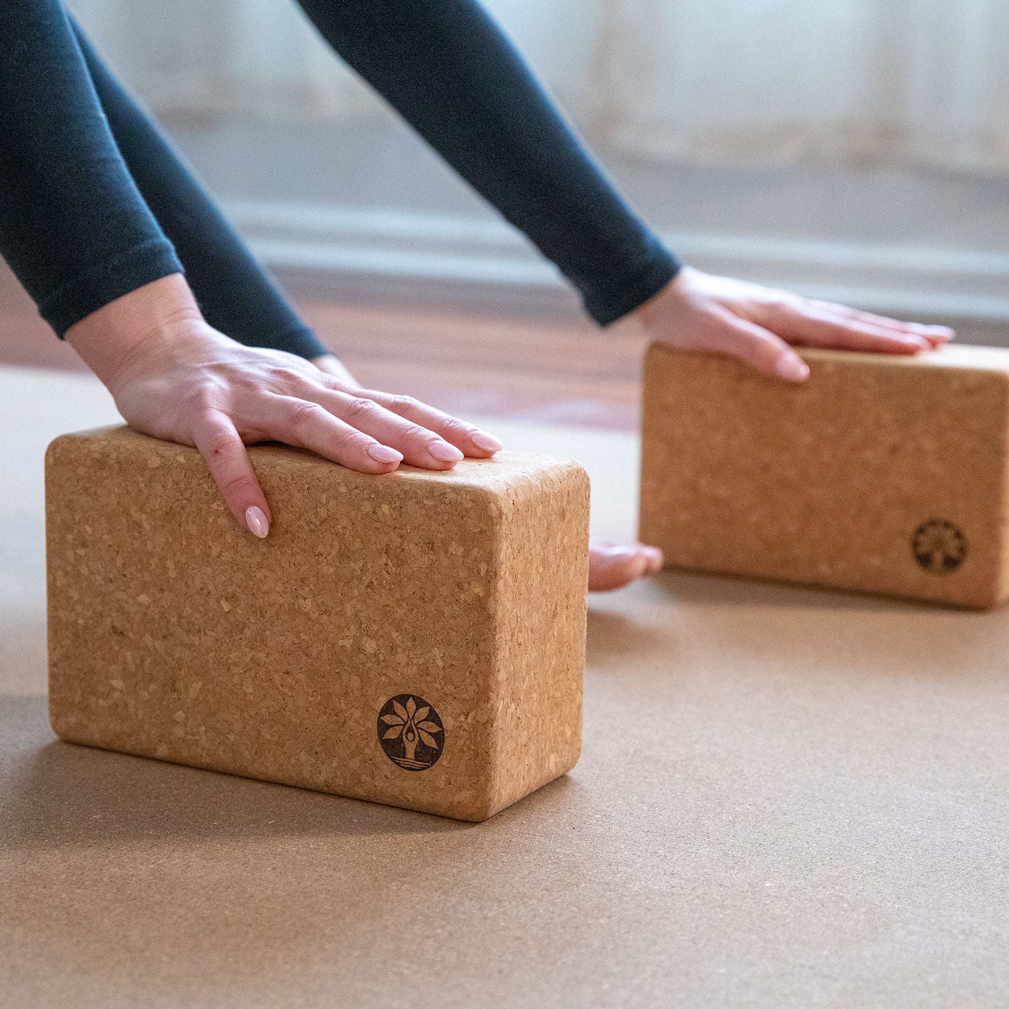 Cork yoga blocks on a mat with hands reaching towards them