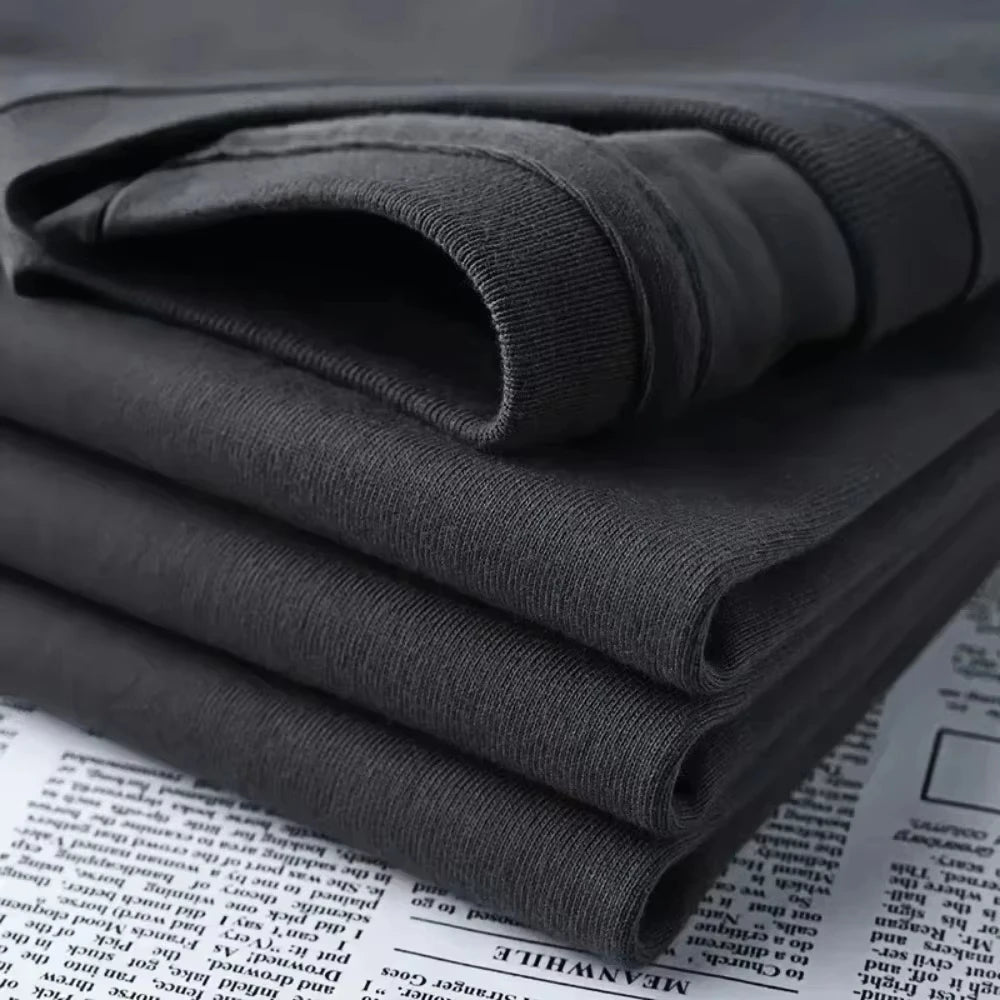Folded dark gray sweatshirt on a newspaper background
