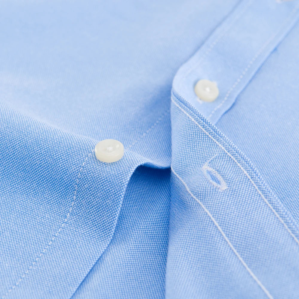 Close-up of a light blue shirt with a button and collar detail.