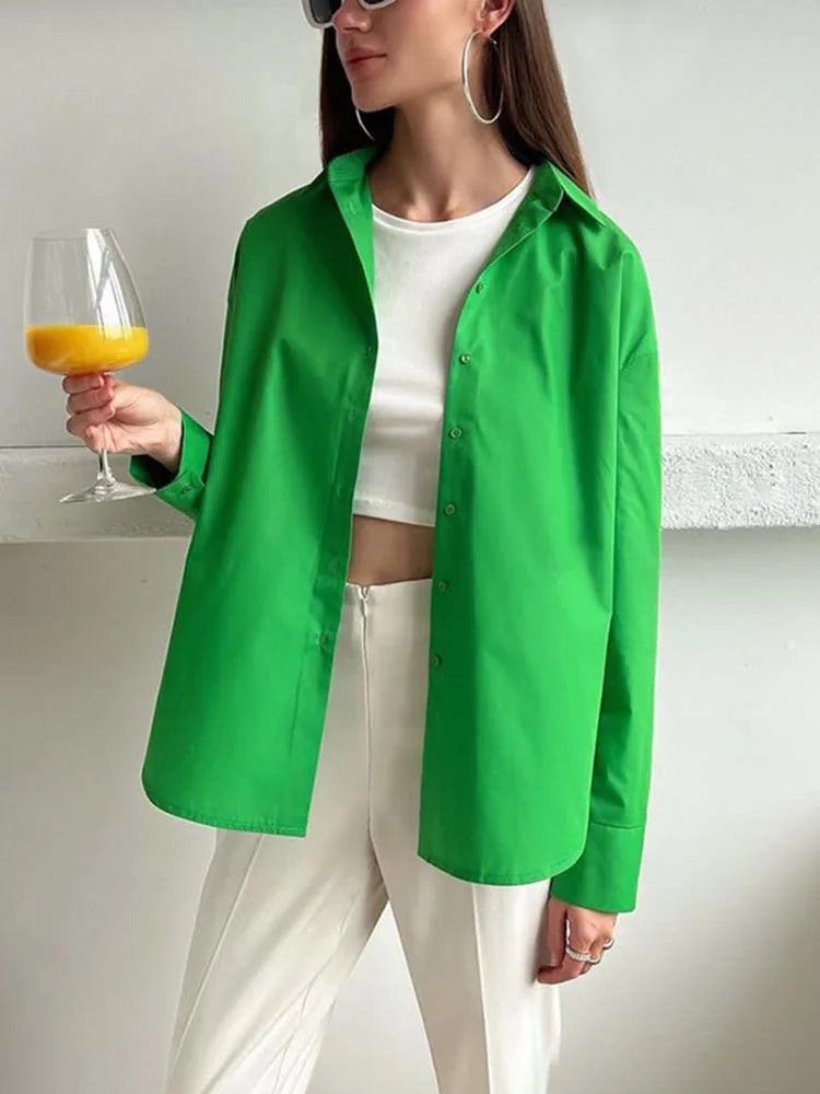 Person wearing a green shirt and white pants, holding a glass with a yellow drink.
