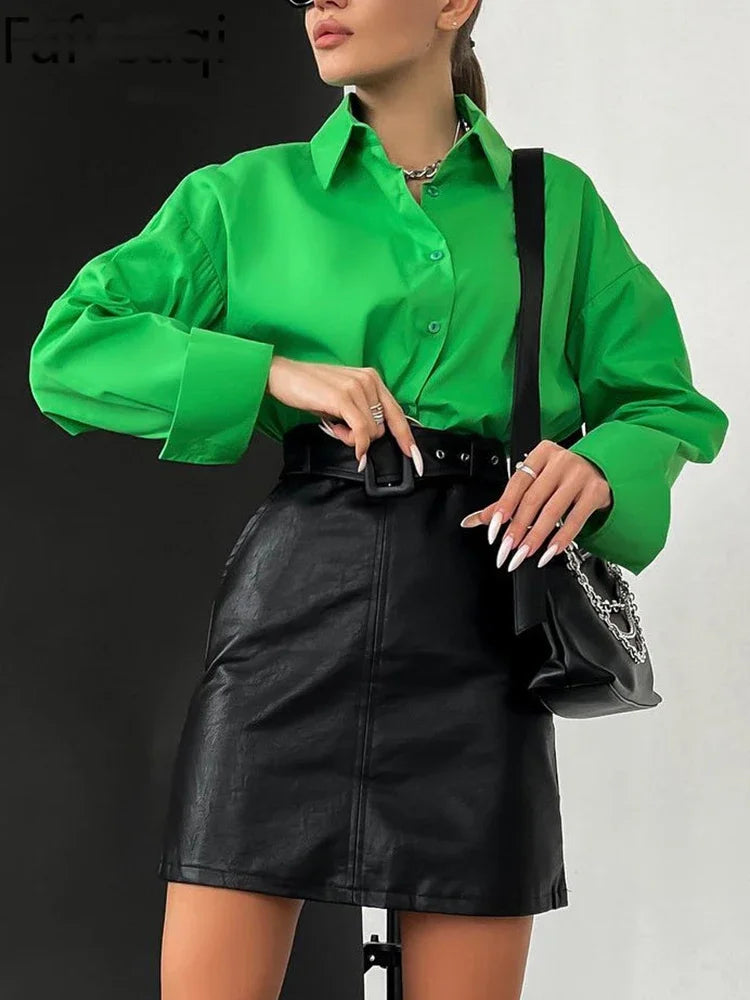 Person wearing a green shirt and black leather skirt with a black handbag on a white background