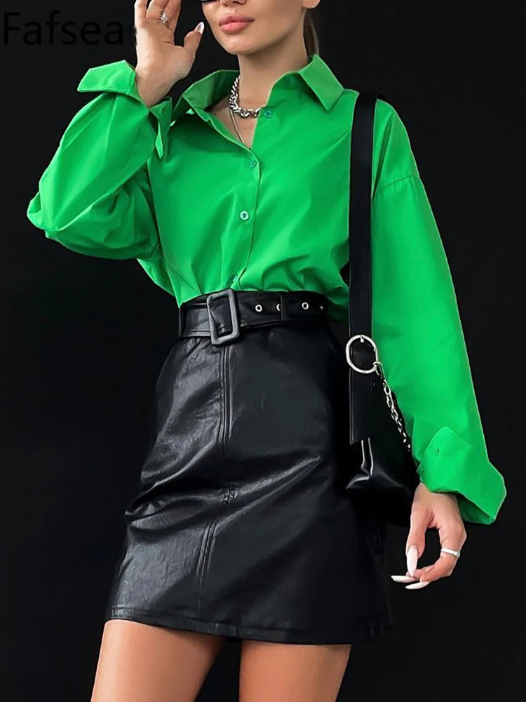 Person wearing a green shirt and black leather skirt with a black bag on a black background