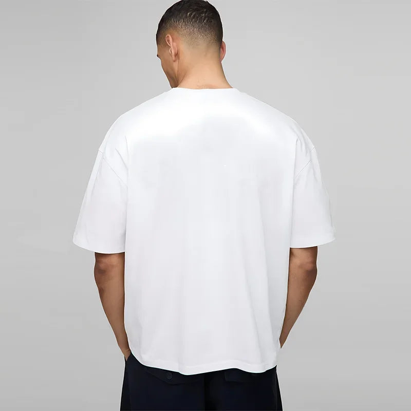 Person wearing a plain white t-shirt against a gray background