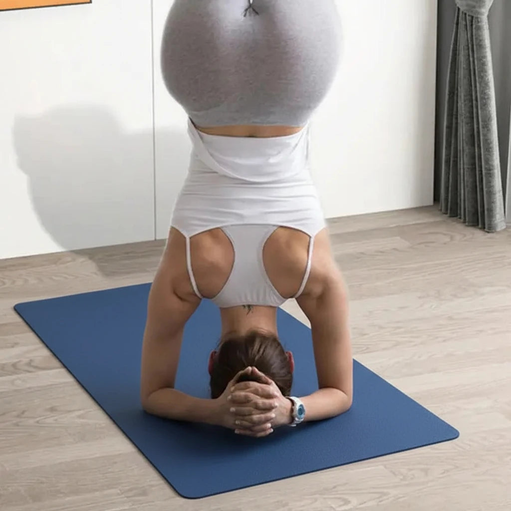 Person practicing yoga on a blue mat with a white wall and wooden floor in the background