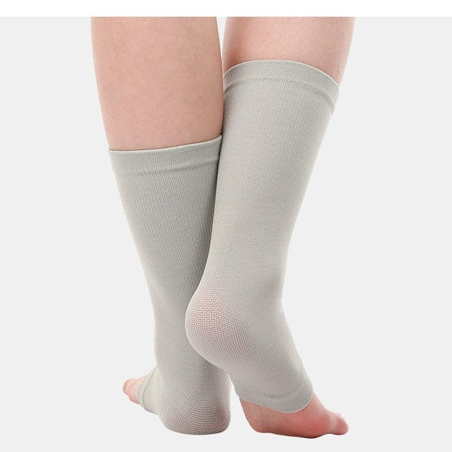 A pair of light gray compression ankle sleeves worn on a person's legs, shown against a plain light gray background.