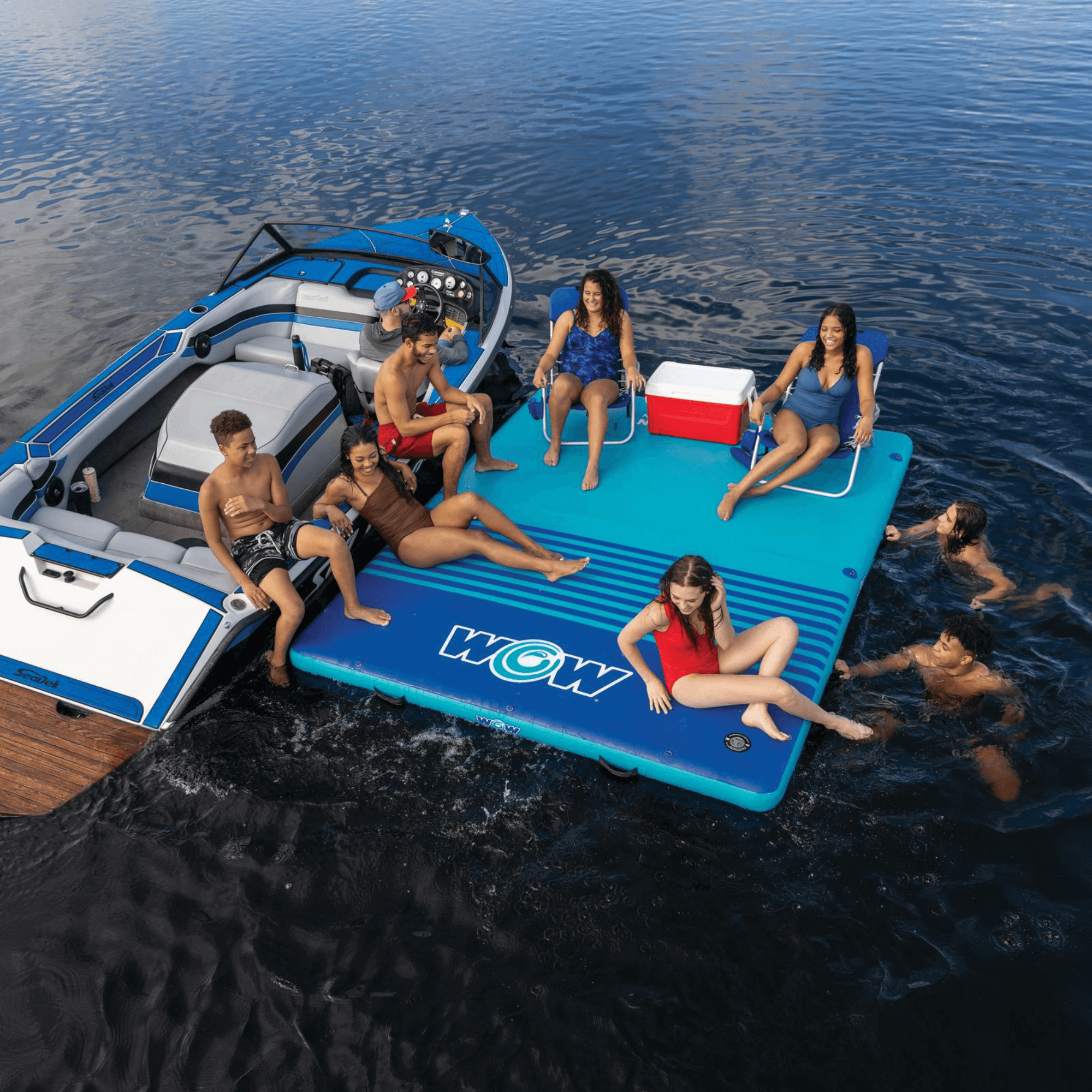 People enjoying a day on a blue inflatable platform with 'WOW' branding in the water.