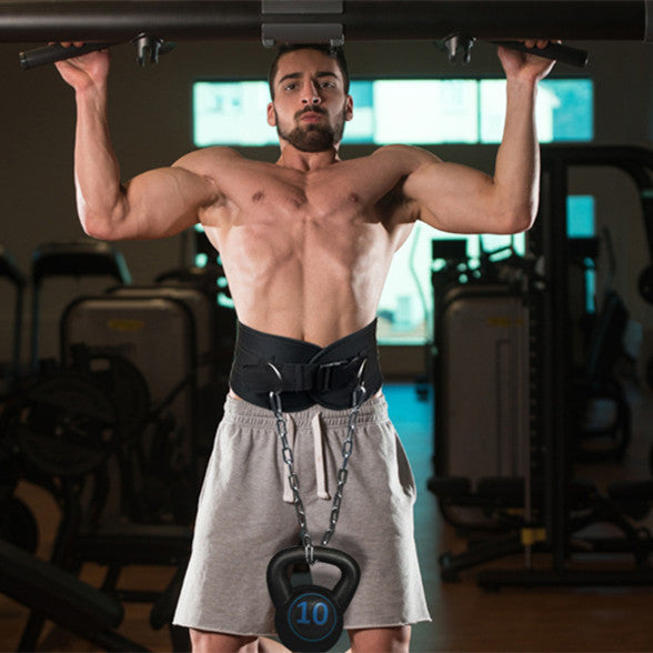 Man performing pull-ups with a kettlebell hanging from his waist in a gym setting