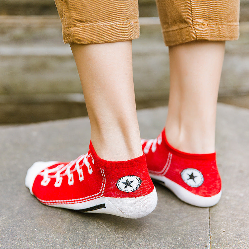 Red sneakers with white soles worn by a person on a concrete surface.