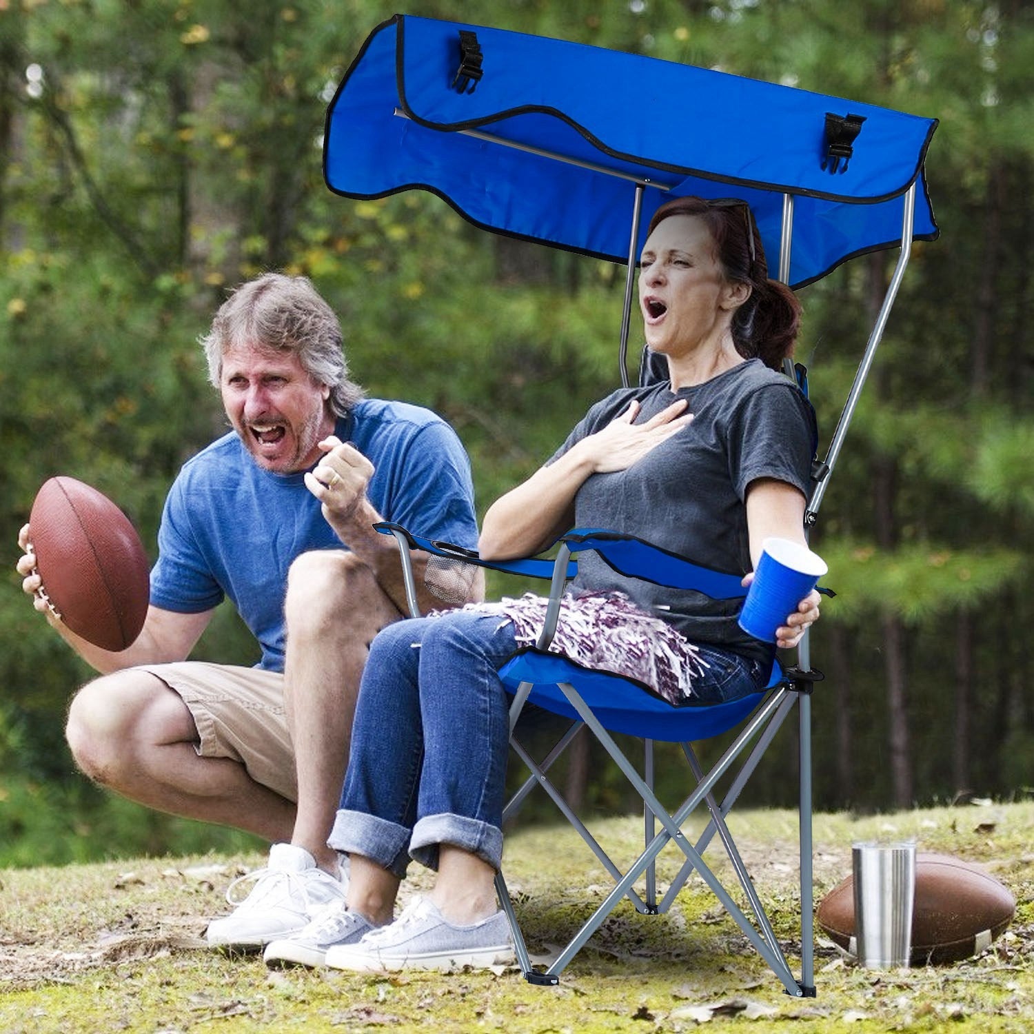 Two people with a blue portable chair and canopy in an outdoor setting.