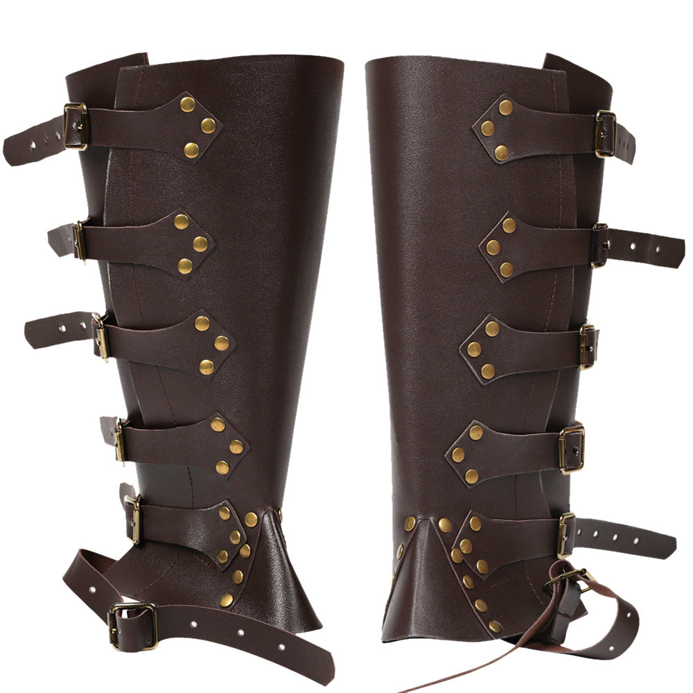 Pair of brown leather leg guards with gold studs and straps on a white background
