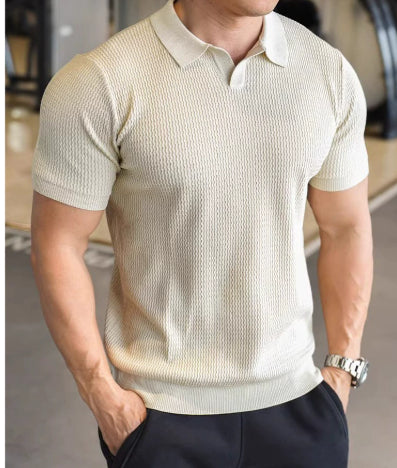 Man wearing a beige short-sleeve knit shirt with a collar indoors.