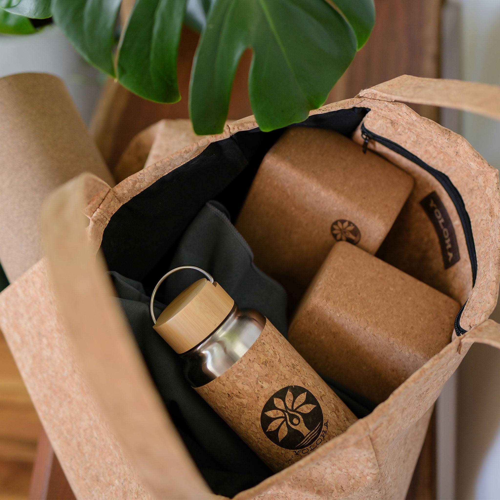 Cork tote bag with cork water bottle and accessories on a wooden surface.