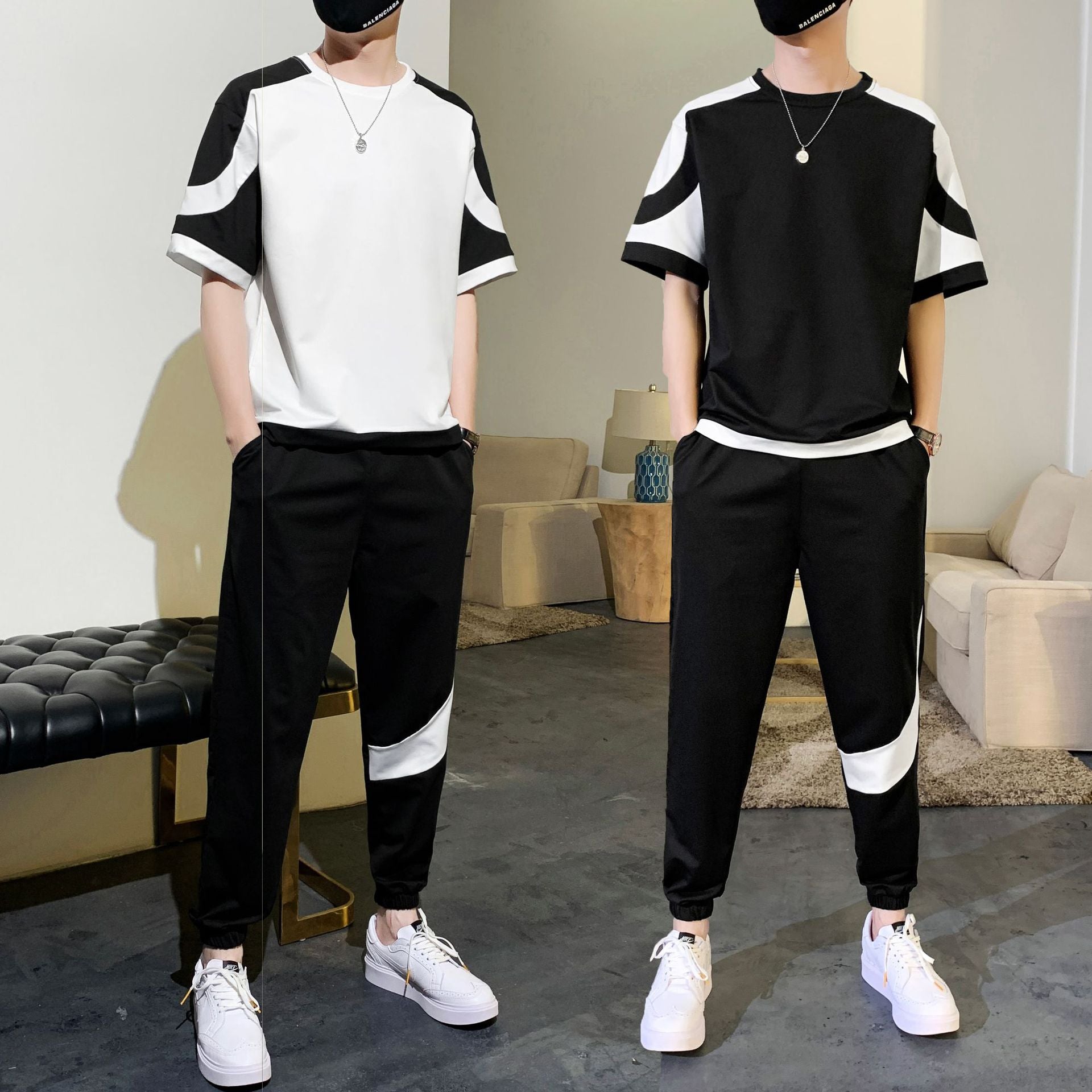 Two people wearing matching black and white outfits in a living room setting.