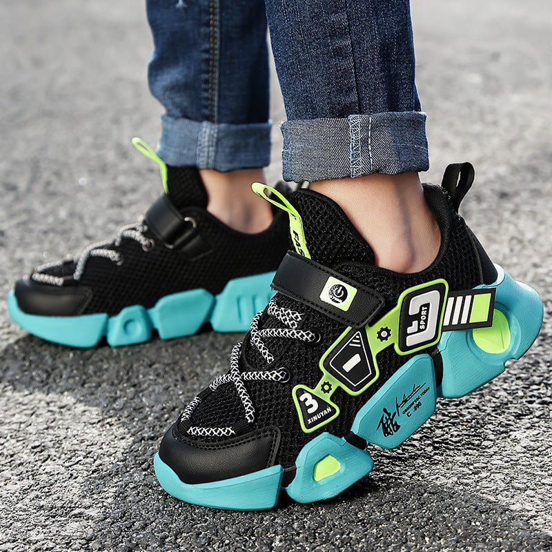 Children's black and teal sneakers with neon accents on a gray pavement background