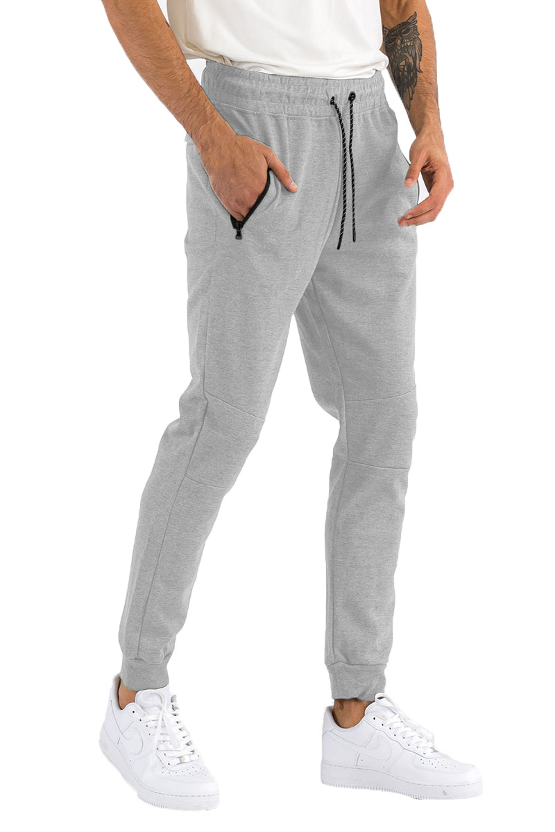 Person wearing gray jogger pants with a white background